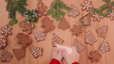 Noel kurabiyelerinin üzerine beyaz krema çizmek, yeni yıl süslemeleri ile süslenmiş masa.