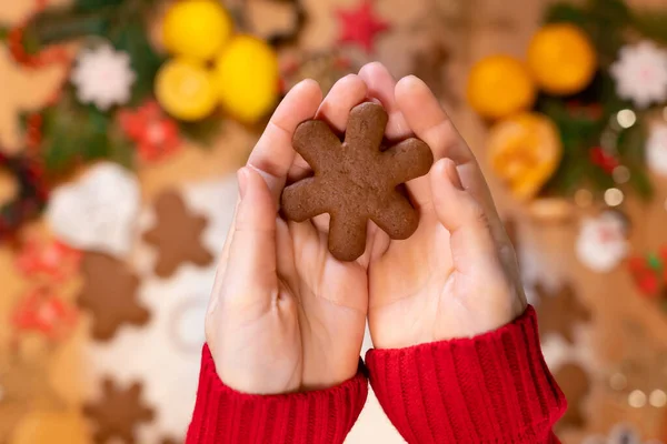 Noel arkaplanındaki bir kızın ellerinde kar taneleri şeklinde zencefilli çörekler, yakın plan, üst manzara