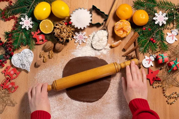 Kadın eli hamuru bir oklavayla yuvarlıyor Noel kurabiyesi yapmak için Noel süslemeleri, üst manzara