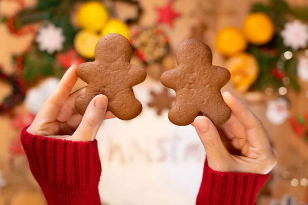 Noel zencefilli çörekler, bir kızın ellerinde, yeni yıl dekorunun arka planında, yakın planda, en üstte.