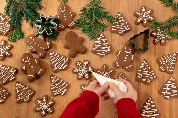 Kız taze pişmiş zencefilli çörekleri beyaz jöleli ve mastiklerle süslenmiş bir masaya çiziyor.