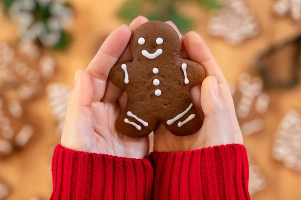 Noel zencefilli çörekler, bir kızın ellerinde, yeni yıl dekorunun arka planında, yakın planda, en üstte.