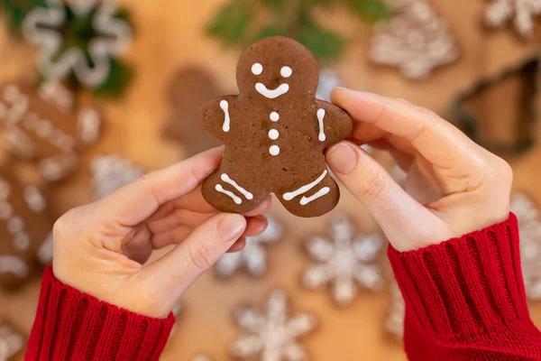 Noel zencefilli çörekler, bir kızın ellerinde, yeni yıl dekorunun arka planında, yakın planda, en üstte.