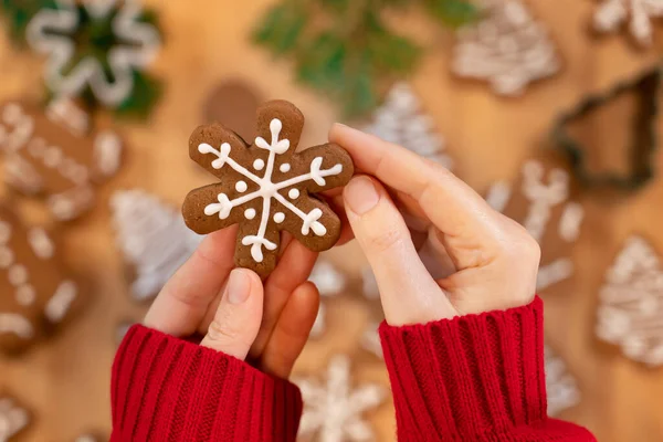 Noel arkaplanındaki bir kızın ellerinde kar tanesi şeklinde zencefilli ekmek, yakın plan, üst manzara