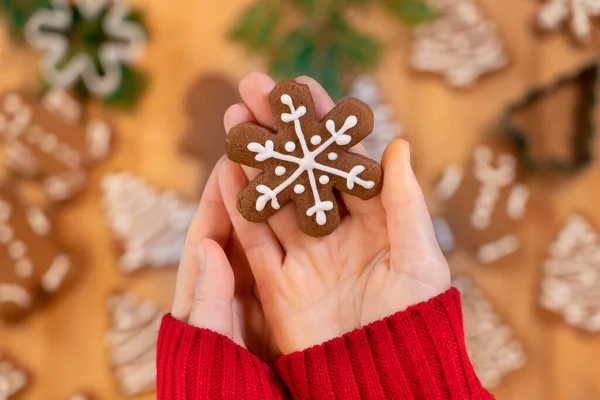 Noel arkaplanındaki bir kızın avuçlarında kar taneleri şeklinde zencefilli çörekler, yakın plan, üst manzara