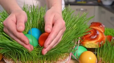 Dişi eller, Paskalya yumurtalarının bulunduğu mikro yeşili yavaşça açar. Bayramlık Paskalya tavşanları masanın üstünde, ön tarafta.