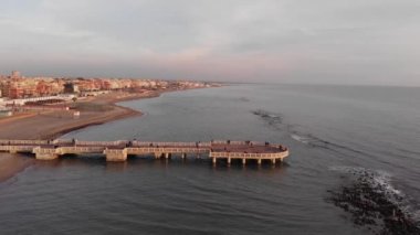 Cinematic Drone pov fly over cliff of Rome with city skyline and pedestrian pier and famous Ravennati Square with a look at the surrounding coast