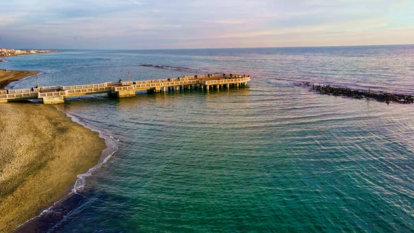青い海と茶色の砂の上にOstia Lidoビーチで日没ローマの航空ビュー 歩行者用桟橋を垣間見る美しい海岸線観光客や都市生活のランドマーク — ストック写真
