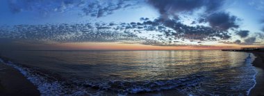 Immersive overview of a sensational unmissable sunset over sea with fantastic sky with mammatus and cirrus clouds paint the firmament enveloped in romantic blue light