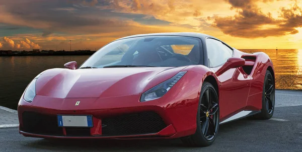 Kırmızı araba modeli Ferrari 488 GTB 'nin hızlı ve lüks tasarımı altın gün batımlı fantastik bir arka planda yer almaktadır. Ferrari 488, İtalya 'nın başkenti Roma' da 2015 yılından bu yana üretilen spor otomobildir.