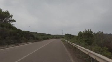 Pov wide angle view driving on empty street between countrysides of Carloforte, Italy