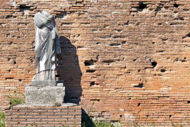 Roma 'nın Ostia Antica şehrinde bulunan ve çok iyi korunmuş antik bir tuğla duvar olan toga kaplı mermer heykel harabeleriyle antik Roma sanatı..