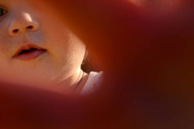 Renkli fotoğraf için poz veren çocuk yüzlü güzel bir oğlan. Cadre, çocuk görünümlü bir erkek bebekten, beyaz bir yüz ifadesinden oluşuyor. Sağlıklı erkek bebek, çocuk yüzü. İyi bir atış için rahatlıyor..