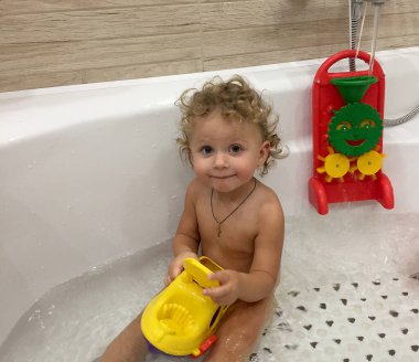 Renkli fotoğraf için poz veren çocuk yüzlü güzel bir oğlan. Cadre, çocuk görünümlü bir erkek bebekten, beyaz bir yüz ifadesinden oluşuyor. Sağlıklı erkek bebek, çocuk yüzü. İyi bir atış için rahatlıyor..