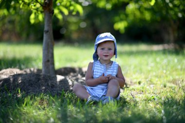 Renkli fotoğraf için çocuk bahçesinde poz veren güzel bir erkek bebek. Cadre, çocuk bahçesindeki erkek bebekten, beyaz bir yüz ifadesinden oluşuyor. Sağlıklı erkek bebek çocuk bahçesinde iğne için dinleniyor..