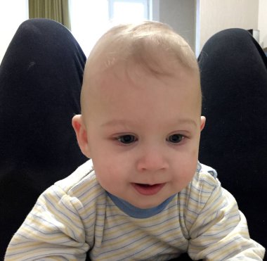 Renkli fotoğraf için poz veren çocuk yüzlü güzel bir oğlan. Cadre, çocuk görünümlü bir erkek bebekten, beyaz bir yüz ifadesinden oluşuyor. Sağlıklı erkek bebek, çocuk yüzü. İyi bir atış için rahatlıyor..