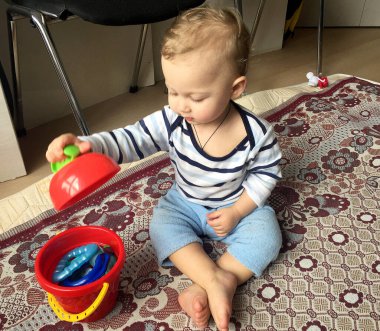 Renkli fotoğraf için poz veren çocuk yüzlü güzel bir oğlan. Cadre, çocuk görünümlü bir erkek bebekten, beyaz bir yüz ifadesinden oluşuyor. Sağlıklı erkek bebek, çocuk yüzü. İyi bir atış için rahatlıyor..