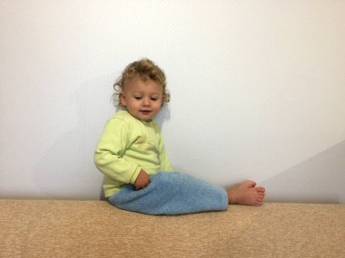 Renkli fotoğraf için poz veren çocuk yüzlü güzel bir oğlan. Cadre, çocuk görünümlü bir erkek bebekten, beyaz bir yüz ifadesinden oluşuyor. Sağlıklı erkek bebek, çocuk yüzü. İyi bir atış için rahatlıyor..