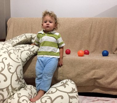 Renkli fotoğraf için poz veren çocuk yüzlü güzel bir oğlan. Cadre, çocuk görünümlü bir erkek bebekten, beyaz bir yüz ifadesinden oluşuyor. Sağlıklı erkek bebek, çocuk yüzü. İyi bir atış için rahatlıyor..