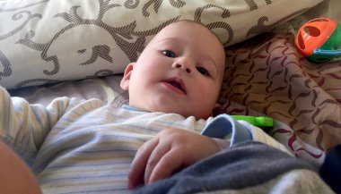 Renkli fotoğraf için poz veren çocuk yüzlü güzel bir oğlan. Cadre, çocuk görünümlü bir erkek bebekten, beyaz bir yüz ifadesinden oluşuyor. Sağlıklı erkek bebek, çocuk yüzü. İyi bir atış için rahatlıyor..