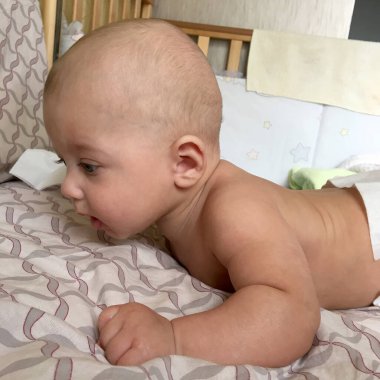 Renkli fotoğraf için poz veren çocuk yüzlü güzel bir oğlan. Cadre, çocuk görünümlü bir erkek bebekten, beyaz bir yüz ifadesinden oluşuyor. Sağlıklı erkek bebek, çocuk yüzü. İyi bir atış için rahatlıyor..