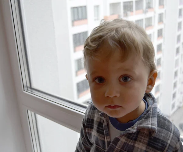 漂亮的男婴 带着孩子的脸在窗前摆着摄影师的姿势拍照 干部由男婴在窗前的儿童形象 白人表情组成 健康的男婴 靠窗的小孩 — 图库照片