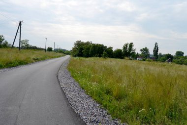 Renkli arka planda, kırsal alanda güzel boş asfalt yol. Fotoğrafçılık, kırsal kesimden geçen yeni boş asfalt yolu içeriyor. Yeşillik kırsalında hız aracı için boş asfalt yol