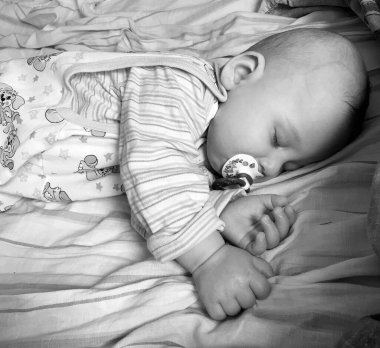 Renkli fotoğraf için fotoğrafçı pozu veren uyuyan erkek bebek, uyuyan bebek emziği, gülümseyen yüz, çocuk emziğindeki sağlıklı uyuyan erkek çocuğu.