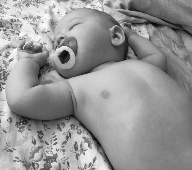 Renkli fotoğraf için fotoğrafçı pozu veren uyuyan erkek bebek, uyuyan bebek emziği, gülümseyen yüz, çocuk emziğindeki sağlıklı uyuyan erkek çocuğu.