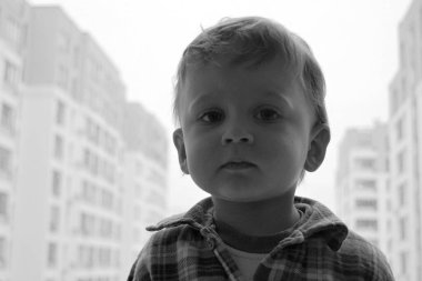 Renkli fotoğraf için pencerenin yanında poz veren çocuk yüzlü güzel erkek bebek, pencerenin yanında çocuk resmi olan erkek bebek, beyaz bir ifade, pencerenin yanında sağlıklı bir erkek çocuğu ve pencerenin yanında da bir çocuk.
