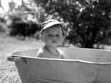 Çocuk küvetinde fotoğrafçı pozu veren güzel bir erkek bebek, çocuk küvetindeki erkek bebekten oluşan bir kadro, beyaz bir yüz, çocuk küveti olan sağlıklı bir erkek bebek, renkli çekim için dinleniyor.