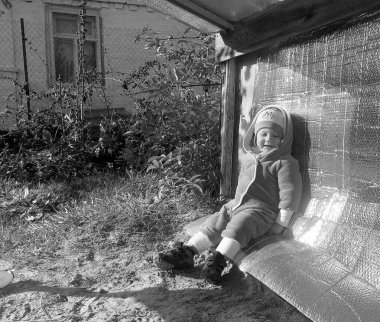 Kum havuzunun yanında fotoğrafçı pozu veren güzel bir bebek. Bebek kum havuzundaki kuru kum tanelerinden oluşur. Küçük çocuklar için ev yapımı kum havuzu. Kumlu bebek kum havuzu, kum havuzu ve çocuk oyunu..