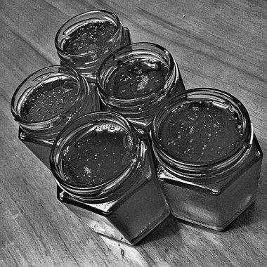 Cam kavanoz dolusu organik bal, ahşap masanın üzerinde duruyor. Lezzetli arı balı cam kavanozdan yapılmış fotoğraf. Arka planda izole edilmiş bal dolu cam kapaklı kavanoz.