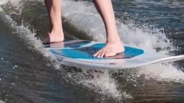 Dalgalarda hızla atlayan sörfçü wakeboard kullanarak kameraya su sıçratıyor.