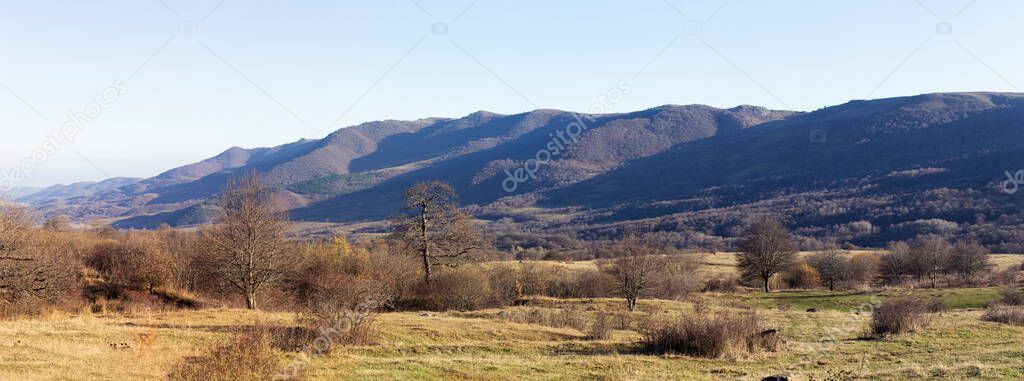 Mountain landscape panorama. A vivid scenic view of the mountain ranges under the blue sky. Yellow foliage, autumn