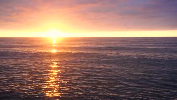 海の上に明るいオレンジ色の夕日 水の中の太陽光のぎらつきによる反射 美しい曇天 — ストック動画