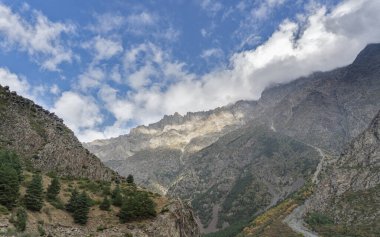 Dağ manzarası manzarası. Güneşli bir günde güzel bir vadi, parlak mavi gökyüzü yumuşak beyaz bulutlarla.