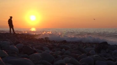 Genç bir adam denizin kenarında dururken fırtınayı seyrediyor. Hareketin dikkati dağıldı