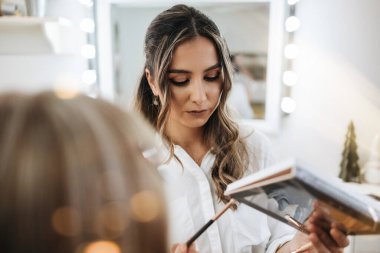 Makyaj süreci. Makyaj için makyaj yapan profesyonel bir sanatçı. Güzellik uzmanının yüzüne odaklan. Parlak ışıklı güzellik salonu.. 