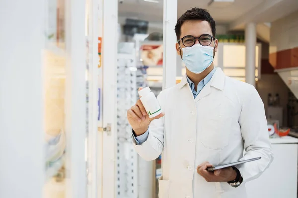 Fiatal Férfi Gyógyszerész Arcvédő Maszkkal Egy Gyógyszertárban Dolgozik Mosolyog Drogot — Stock Fotó