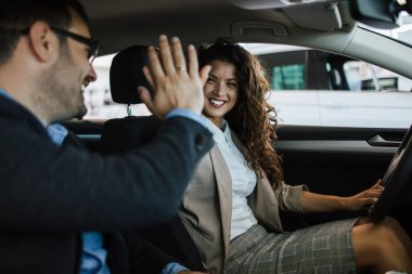 Mutlu orta yaşlı çift galeride yeni araba seçerken ve alırken eğleniyor..