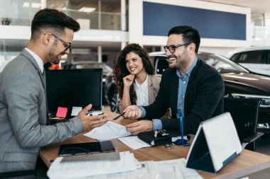 Araba galerisinden araba alan orta yaşlı bir çift. Araba satıcısı doğru karar vermelerine yardımcı oluyor. Adam alıcı sözleşmesi imzalar..