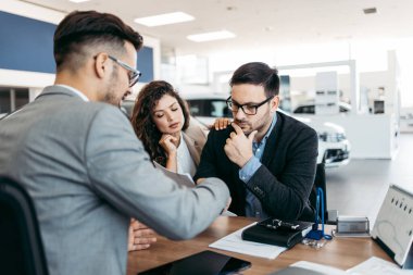 Araba galerisinden araba alan orta yaşlı bir çift. Araba satıcısı doğru karar vermelerine yardımcı oluyor. Adam alıcı sözleşmesi imzalar..