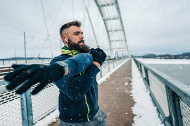 Çok soğuk ve karlı bir günde sakallı, koşan ve dışarıda egzersiz yapan yakışıklı orta yaşlı bir adam. Spor ve spor motivasyon teması.