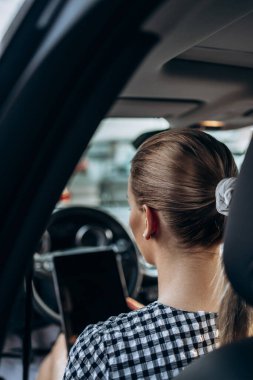 Kullanılmış araba satıcısı olarak çalışan güzel bir genç kadın. Müşteri veya alıcıdan önce dijital tablet kullanıyor ve araba durumunu kontrol ediyor. Kullanılmış araç galerisi.