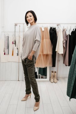 Özel moda stüdyosunda ya da butikte modaya uygun giyinmeye çalışan güzel esmer bir kadın..