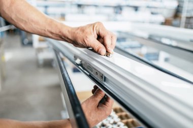 Elle çalışan işçi PVC kapı ve pencereleri birleştiriyor. İmalat işleri. Seçici odaklanma. Alüminyum ve PVC pencere ve kapı üretim fabrikası.