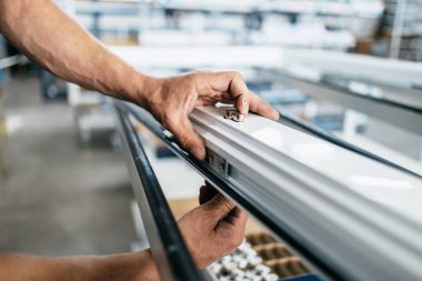 Elle çalışan işçi PVC kapı ve pencereleri birleştiriyor. İmalat işleri. Seçici odaklanma. Alüminyum ve PVC pencere ve kapı üretim fabrikası.