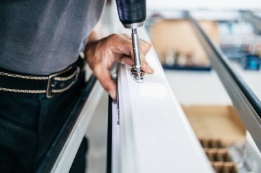 Elle çalışan işçi PVC kapı ve pencereleri birleştiriyor. İmalat işleri. Seçici odaklanma. Alüminyum ve PVC pencere ve kapı üretim fabrikası.