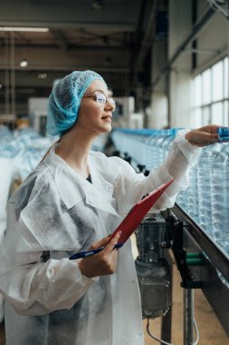 Tıbbi malzeme araştırma ve üretim fabrikasında çalışan ve sevkiyattan önce damıtılmış su kutularını kontrol eden koruyucu işçi. Denetim kalite denetimi. 